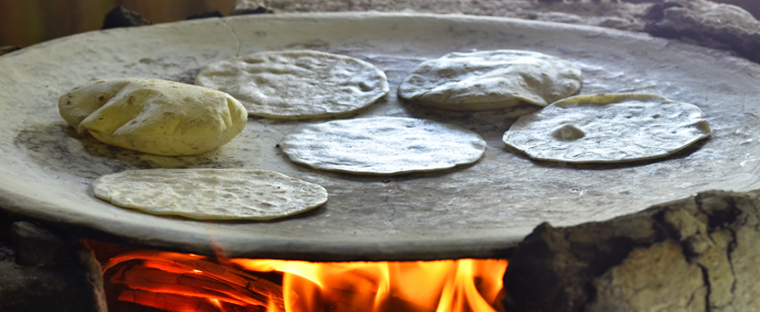 mexican comal over an open fire with tortillas